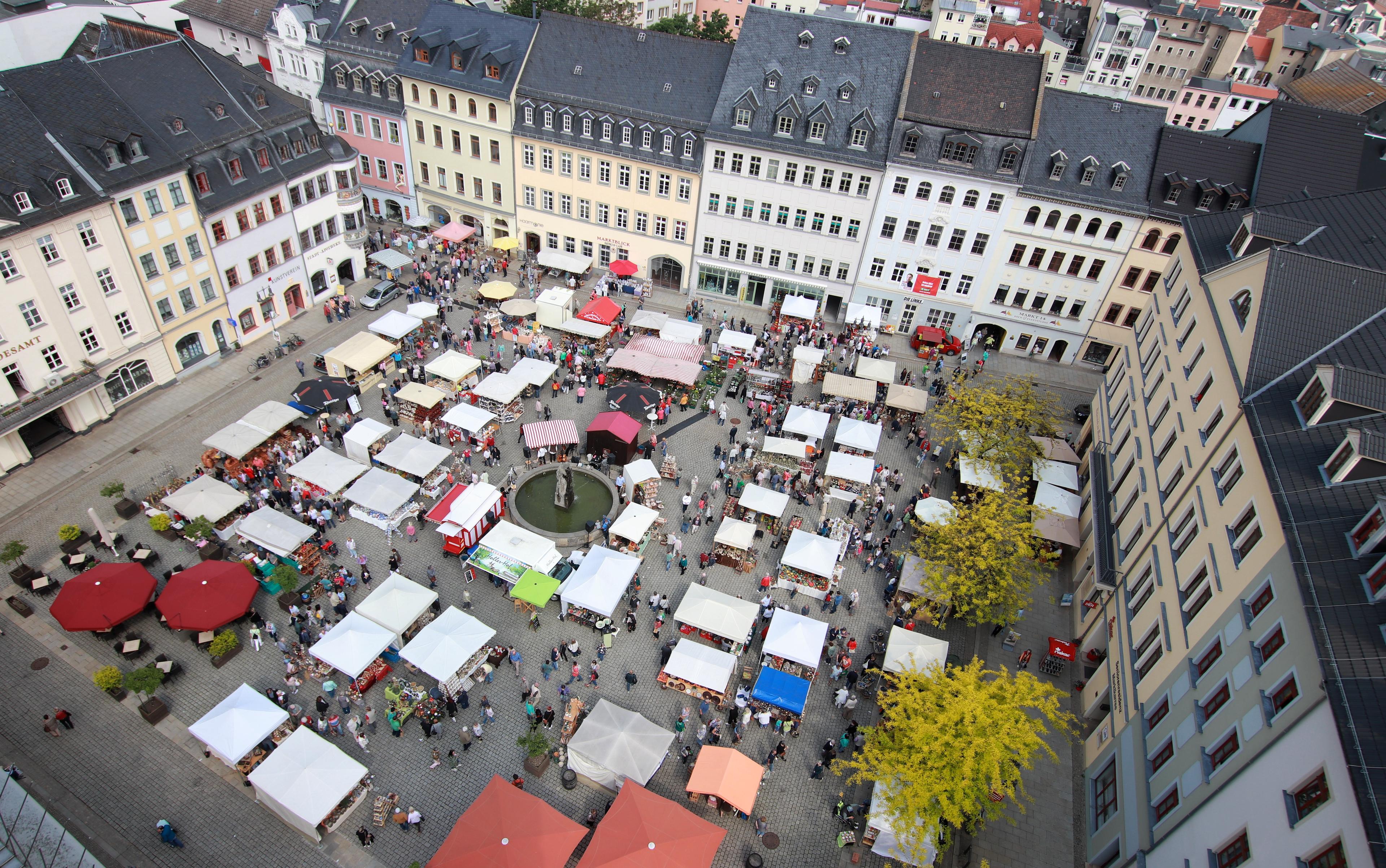 Marktplatz von oben mit vielen Ständen und Besuchern. 