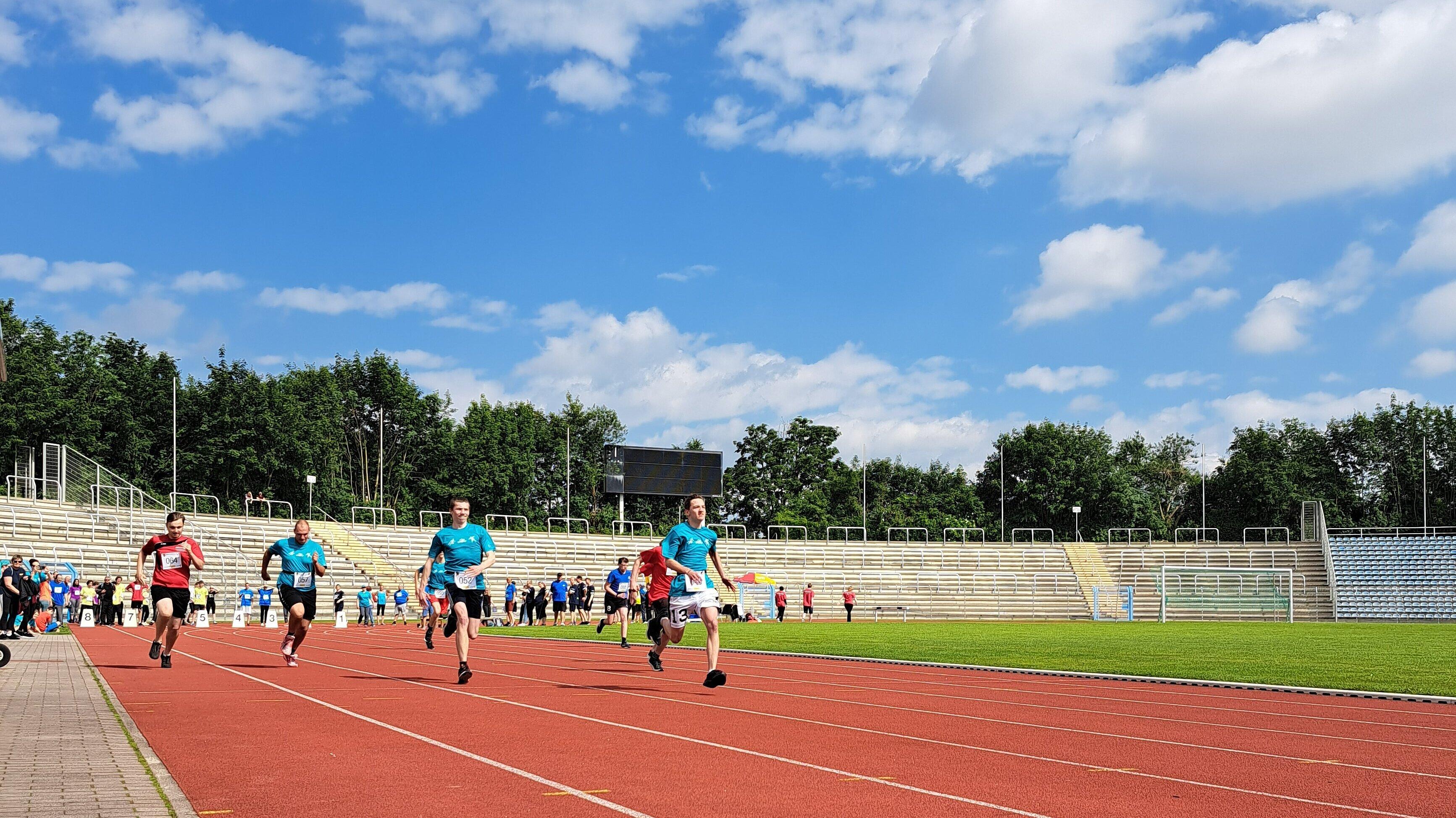 Mehrere Athleten sprinten auf einer Laufstrecke im Stadion