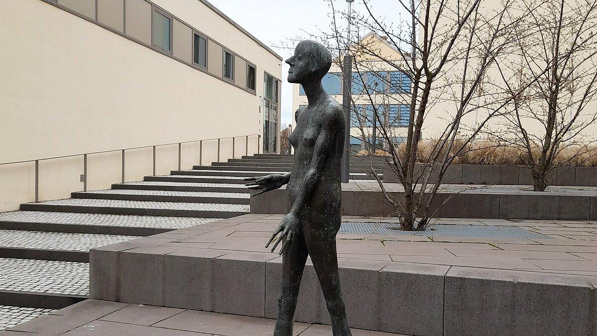 Eine lebensgroße Bronzeskulptur mit dem Namen "Schreitende" steht in der Fußgängerzone