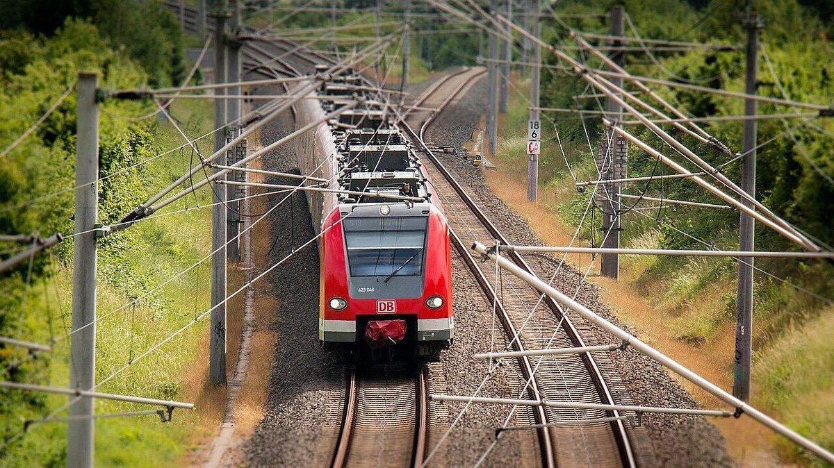 Ein roter Regionalexpress fährt auf einem von zwei Gleisen