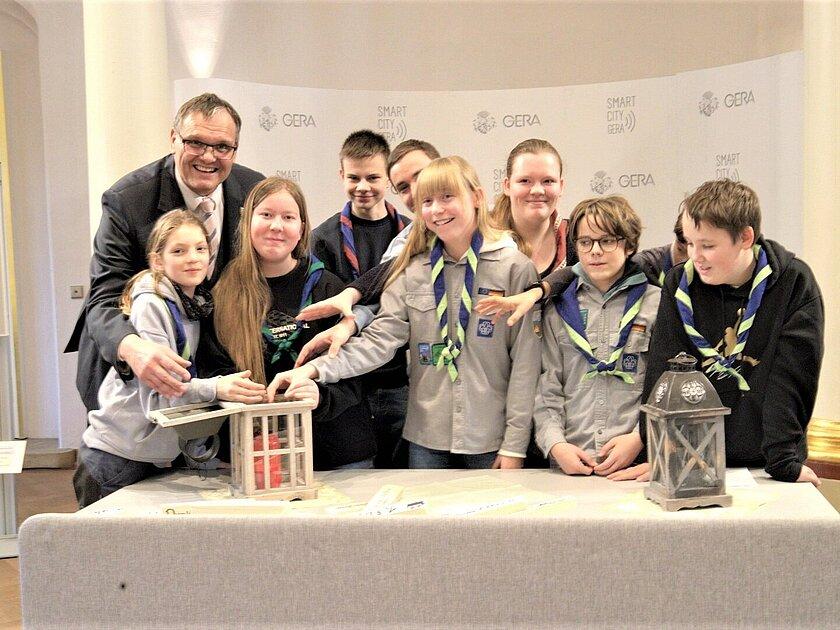 Mehrere Menschen vor einer Laterne, in der das Friedenslicht brennt. © Stadt Gera
