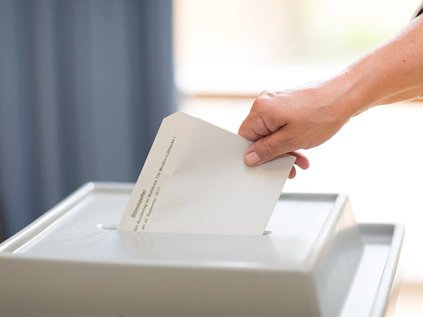 eine Person gibt ihren Stimmzettel ab. © Christian Schwier_stock.adobe.com